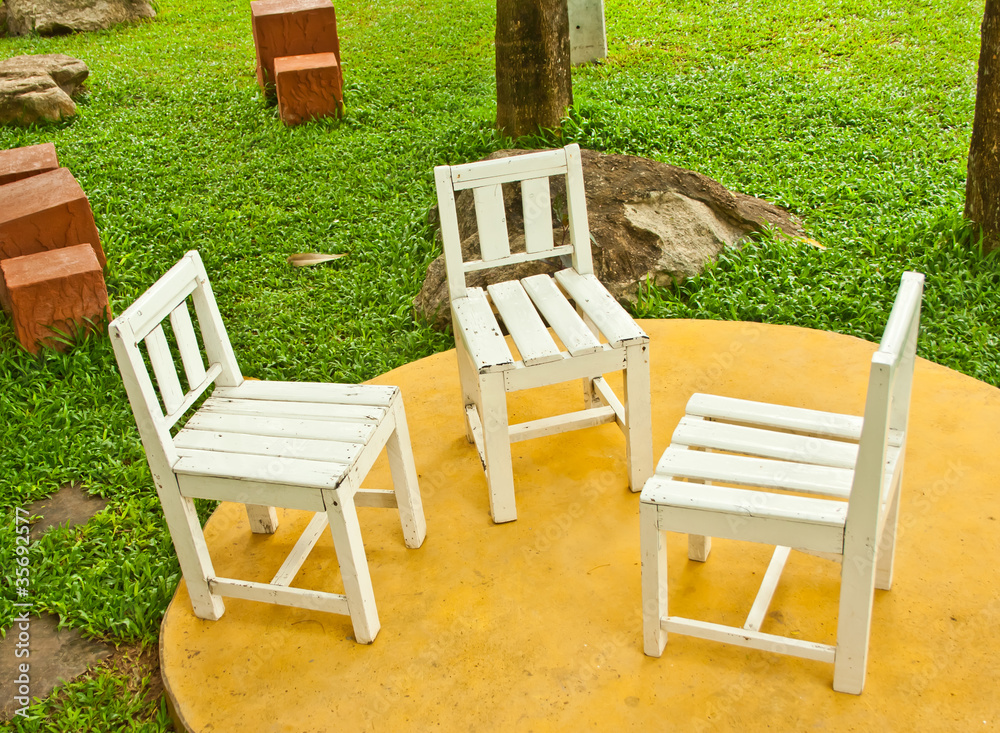three old white chairs setting in garden