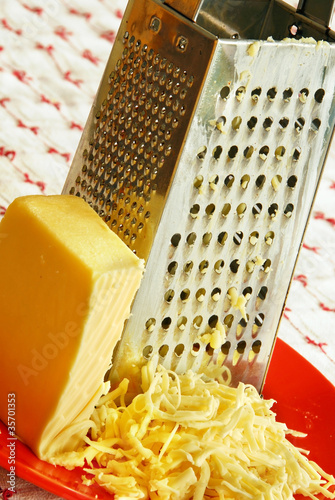 grated yellow cheese with a metal grater closeup photo