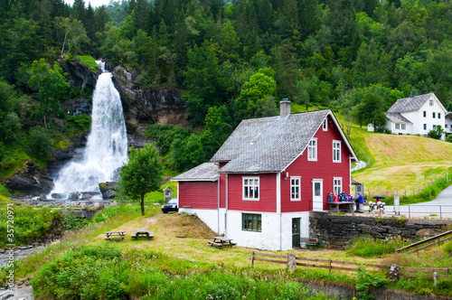 Red wooden house and waterfall Steindalsfossen. Norway