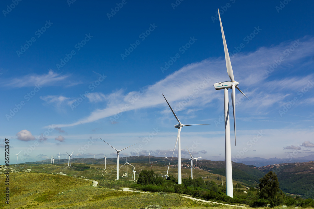 View of a wind farm with a blue sky and clouds.