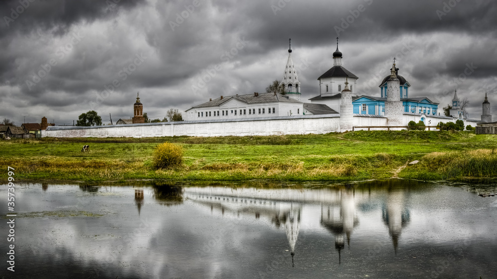 Monastery against the cloudy sky with reflection in lake