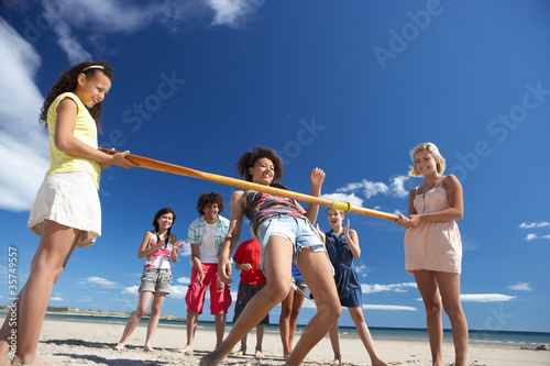 Teenagers doing limbo dance on beach photo