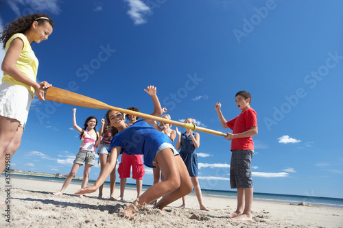 Teenagers doing limbo dance on beach photo