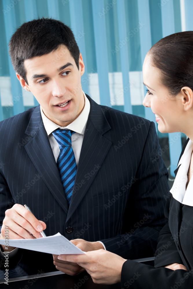 Two businesspeople signing document at office