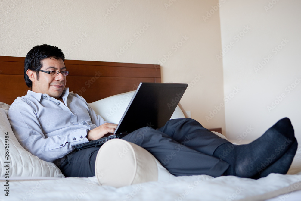 Hispanic businessman using laptop in his hotel room Hispanic businessman using laptop in his hotel room