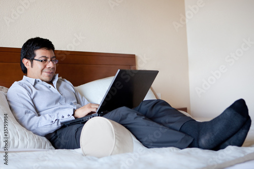 Hispanic businessman using laptop in his hotel room