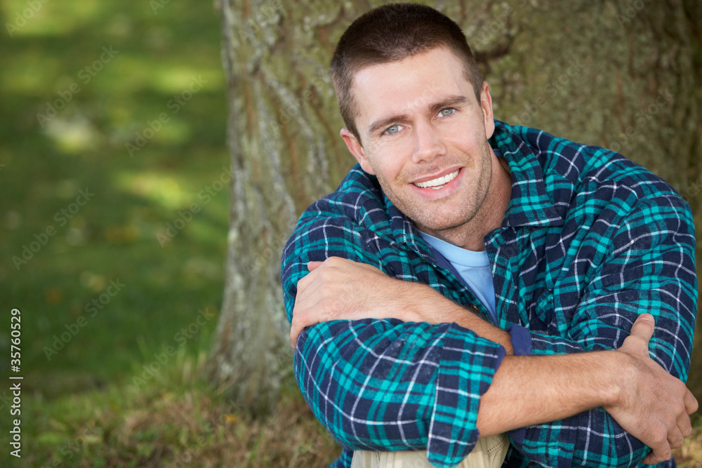 Man sitting against tree trunk Man sitting against tree trunk