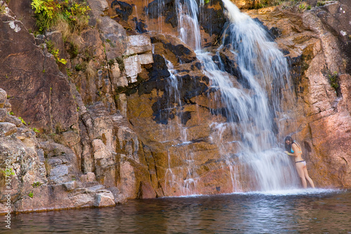 Beauty young woman taking bath in a waterfall