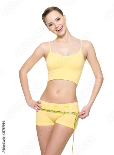 Laughing woman with sexy slim body measuring hips