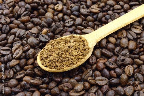 Ground coffee in wooden spoon on a coffee beans background