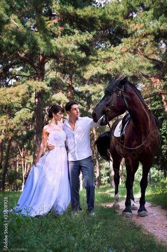 Bride and groom posing in the garden with a horse