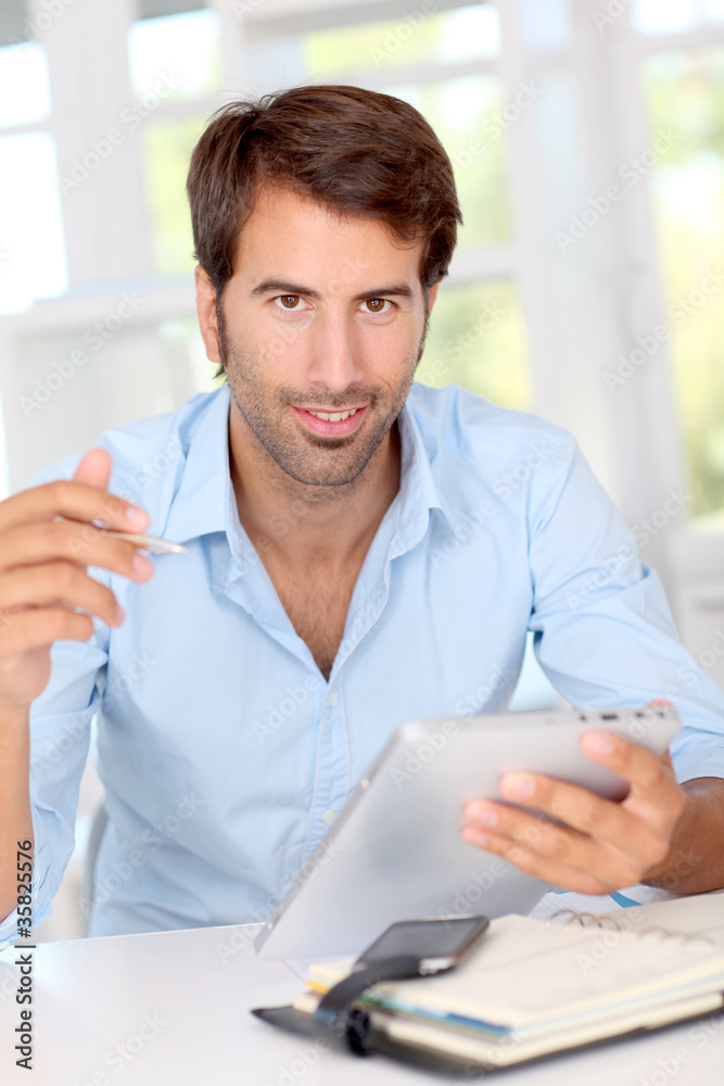 Man working on electronic tablet in office