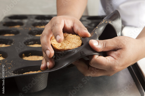 Fototapeta Naklejka Na Ścianę i Meble -  Cuisinier démoulant des gâteaux sur des plaques en silicone