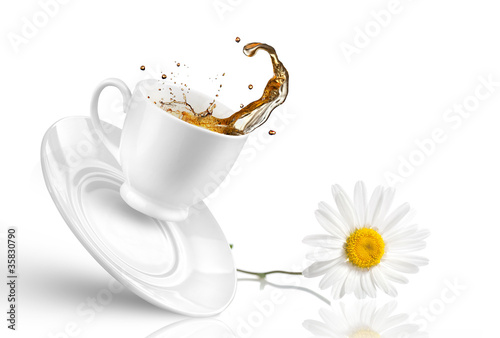 Splash of tea in the falling cup with flower isolated on white