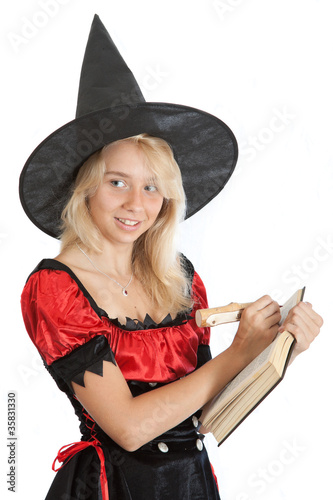 teenager girl in Halloween witch reads magic book photo