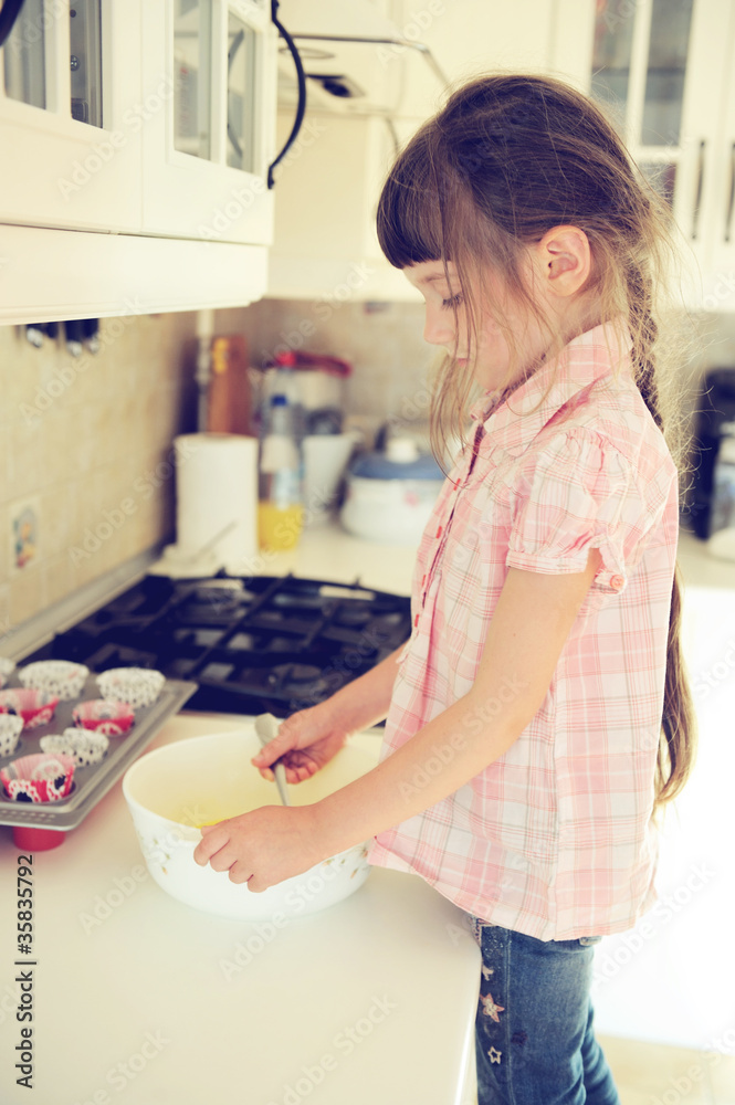 Concentrated child girl making muffins in kitchen Concentrated child girl making muffins in kitchen