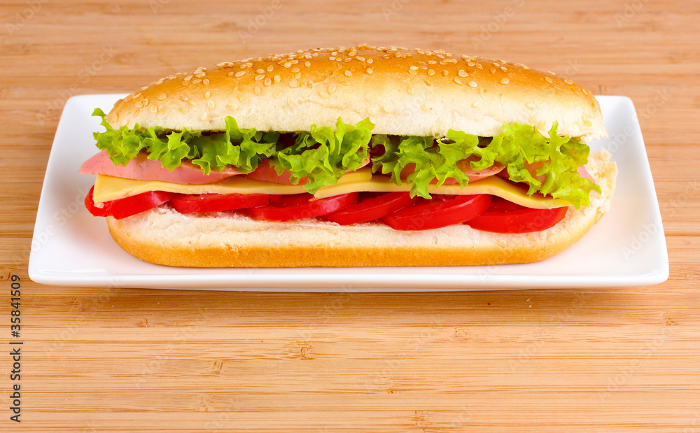 Sandwich with sausage, cheese and tomatoes on plate on wooden ba Sandwich with sausage, cheese and tomatoes on plate on wooden ba