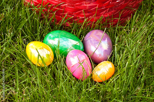 Colored Easter eggs in grass in front of basket