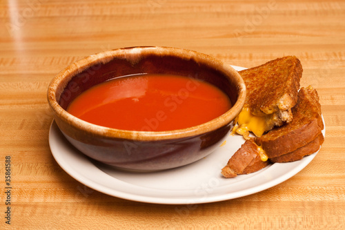 Tomato soup sharing a plate with a cut grilled cheese sandwich