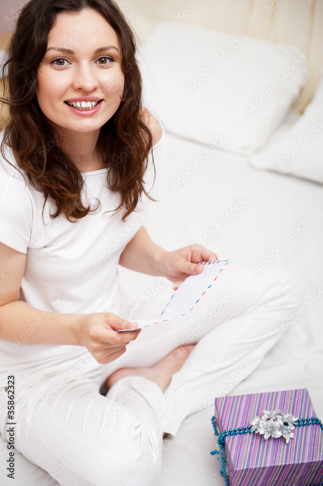 Happy woman reading a letter in her bedroom. She recieved a lett Happy woman reading a letter in her bedroom. She recieved a lett