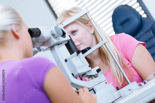 optometry concept - pretty, young female patient having her eyes