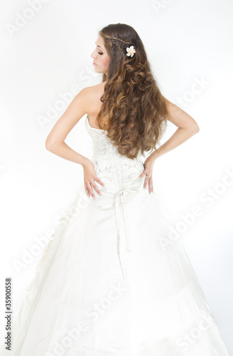 Long curly hair. Bride with hairstyle in wedding dress. Back vie