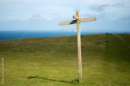 Wooden cross footpath sign with directions to Studland / Swanage