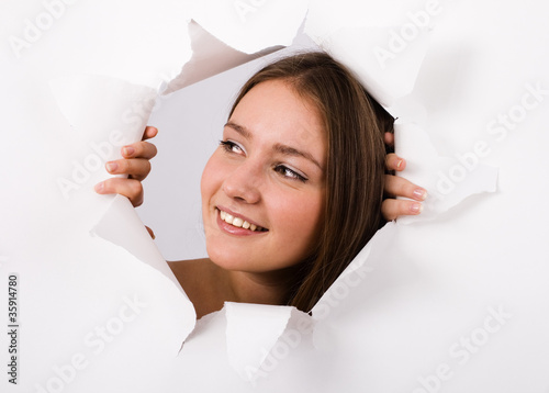 The girl spies through a hole in a paper.