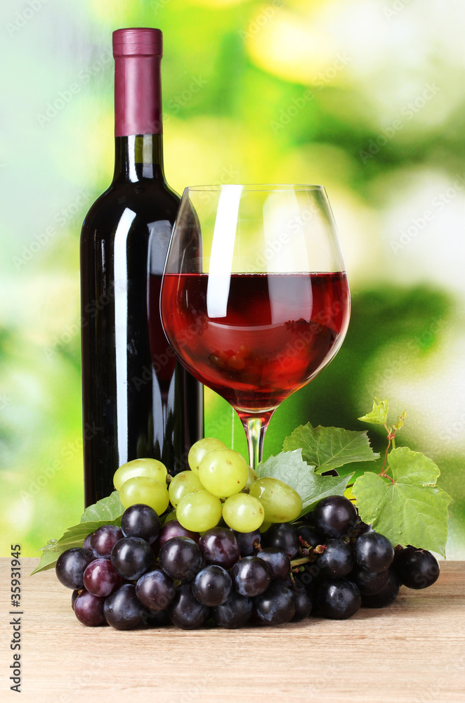 Ripe grapes and  glass of wine on  green background