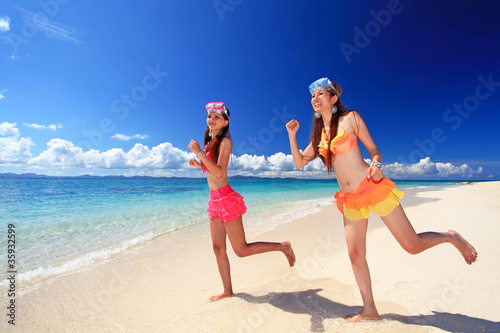 砂浜の上を走る二人の女性