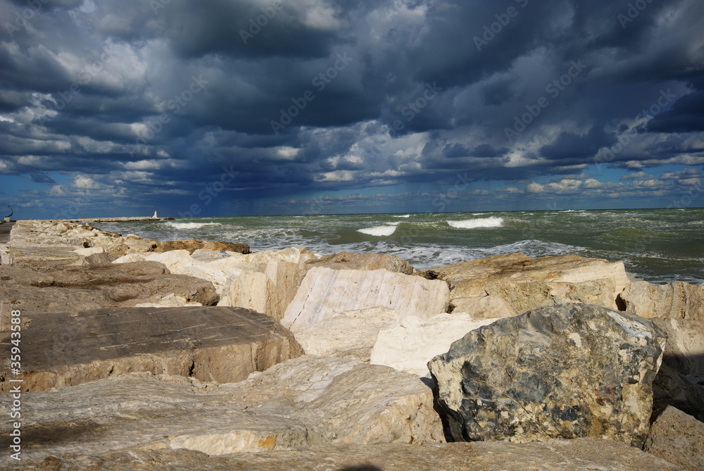 Fotografie waves on the rocks during a cloudy and windy day