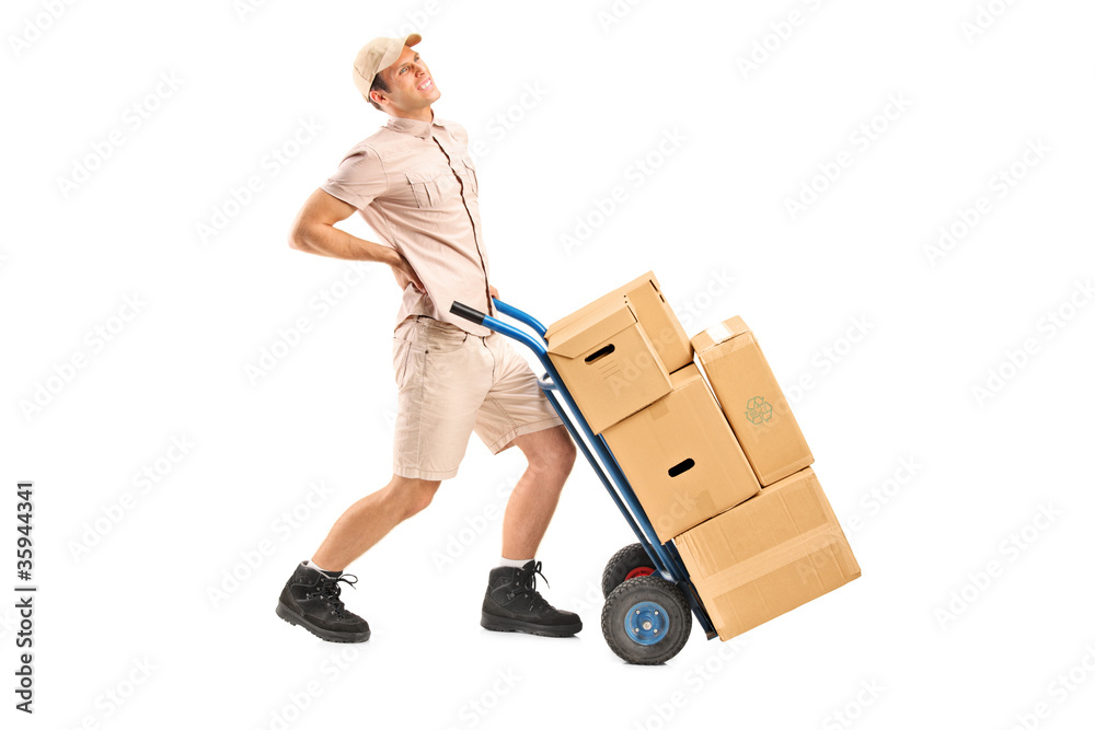 Delivery boy, suffering from a back pain, pushing a hand truck Delivery boy, suffering from a back pain, pushing a hand truck
