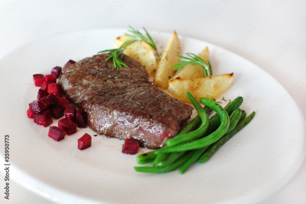 Sirloin with beetroot, beans and potatoes with rosemary on white