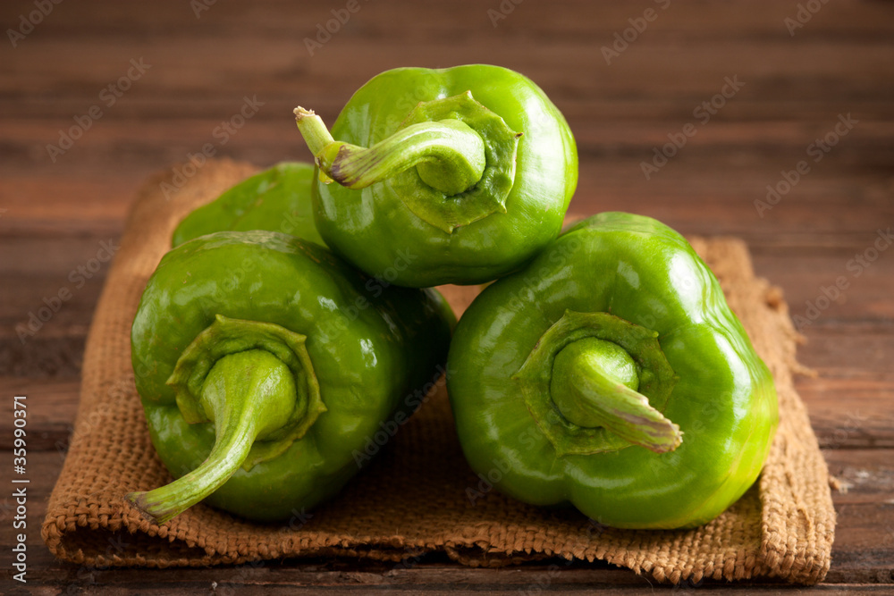 Three Green Bell Peppers on Jute and Wood Three Green Bell Peppers on Jute and Wood