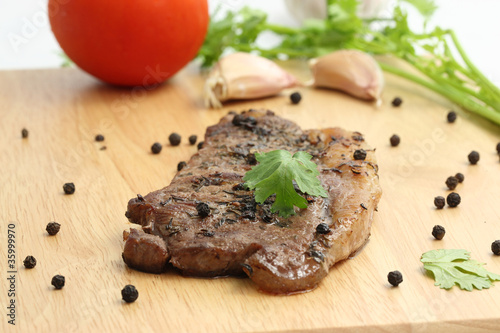 Grilled steak with vegetables on wood background