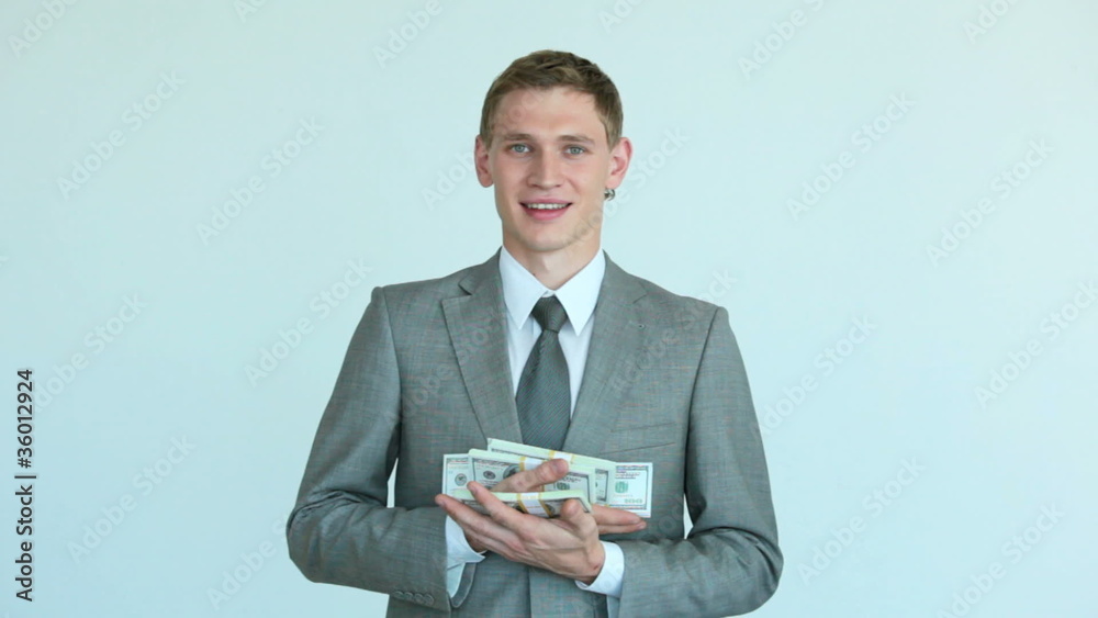 Businessman holding growing heap of dollar bills Businessman holding growing heap of dollar bills