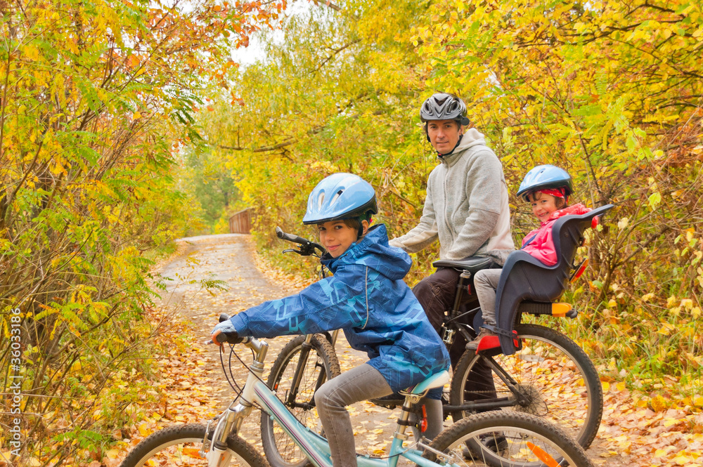 Family cycling outdoors, golden autumn in park