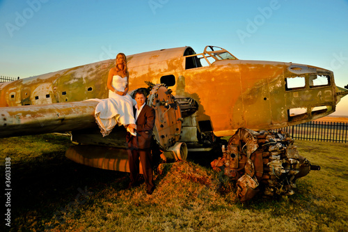 young wedding couple laying on crashed old Dakota war plane photo