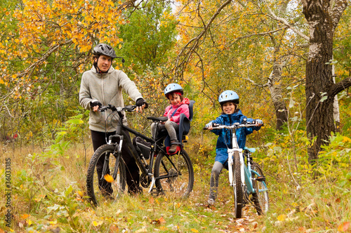 Family cycling outdoors, golden autumn in park