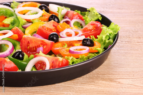 many vegetables in a bowl on wooden background