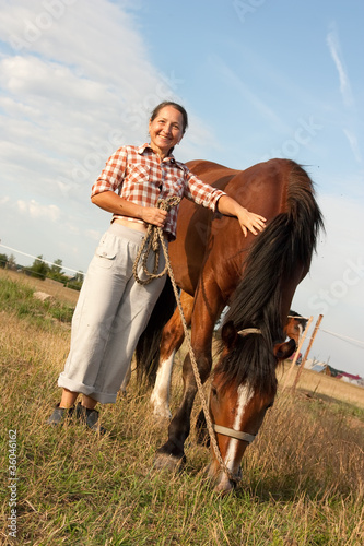 mature woman stands next to horse