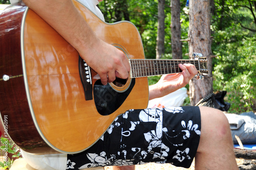 Young man playing acoustic guitar in the nature