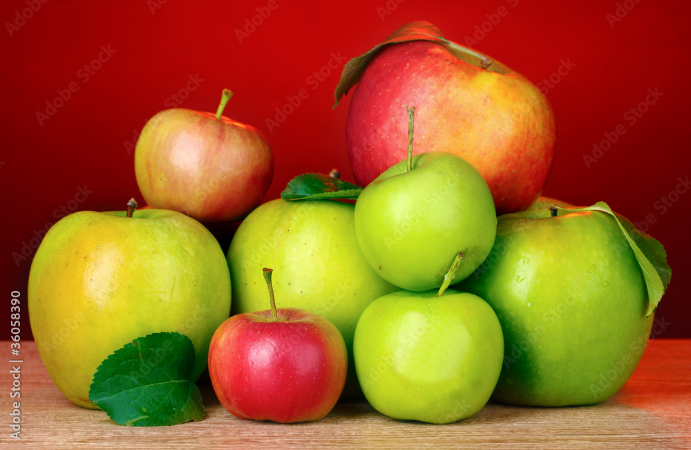 Many fresh organic apples on wooden table on red background Many fresh organic apples on wooden table on red background