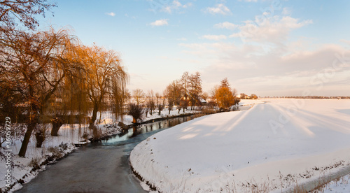 Dutch winter landscape with a curved ditch and snowy fields