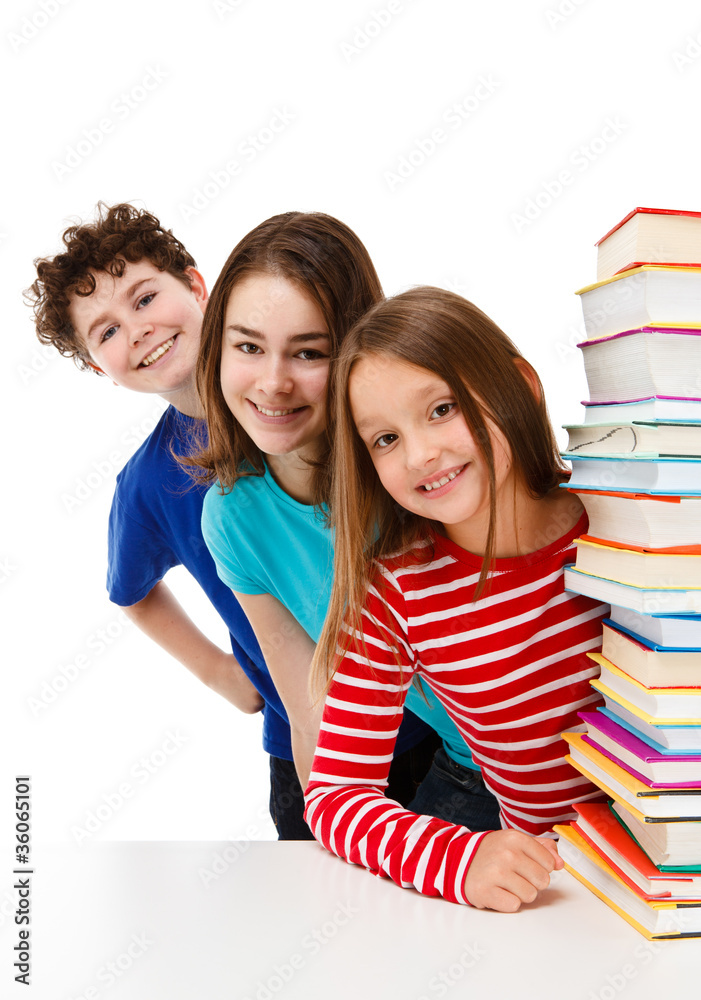 Students peeking behind pile of books on white Students peeking behind pile of books on white