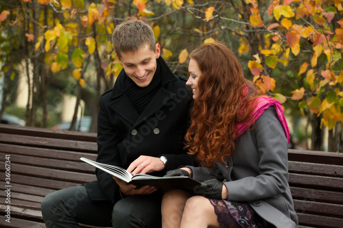 young happy couple with book on the bench