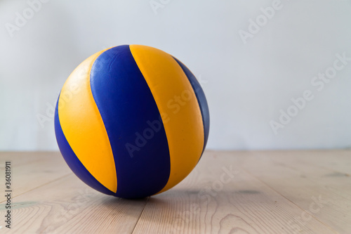 Colorful volleyball ball lying on soft wood floor