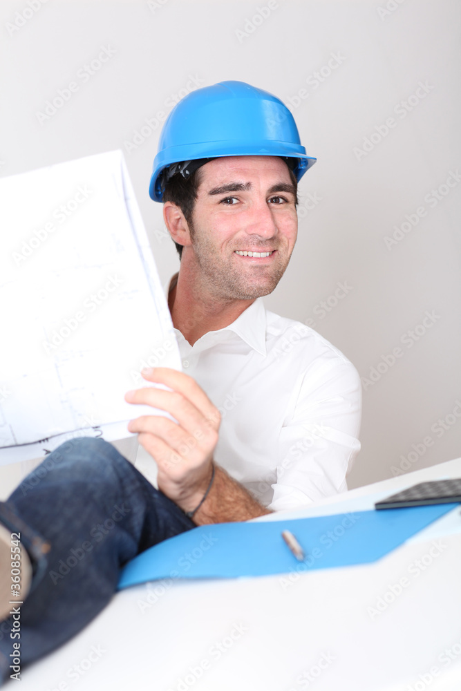Relaxed architect in office with construction plan Relaxed architect in office with construction plan