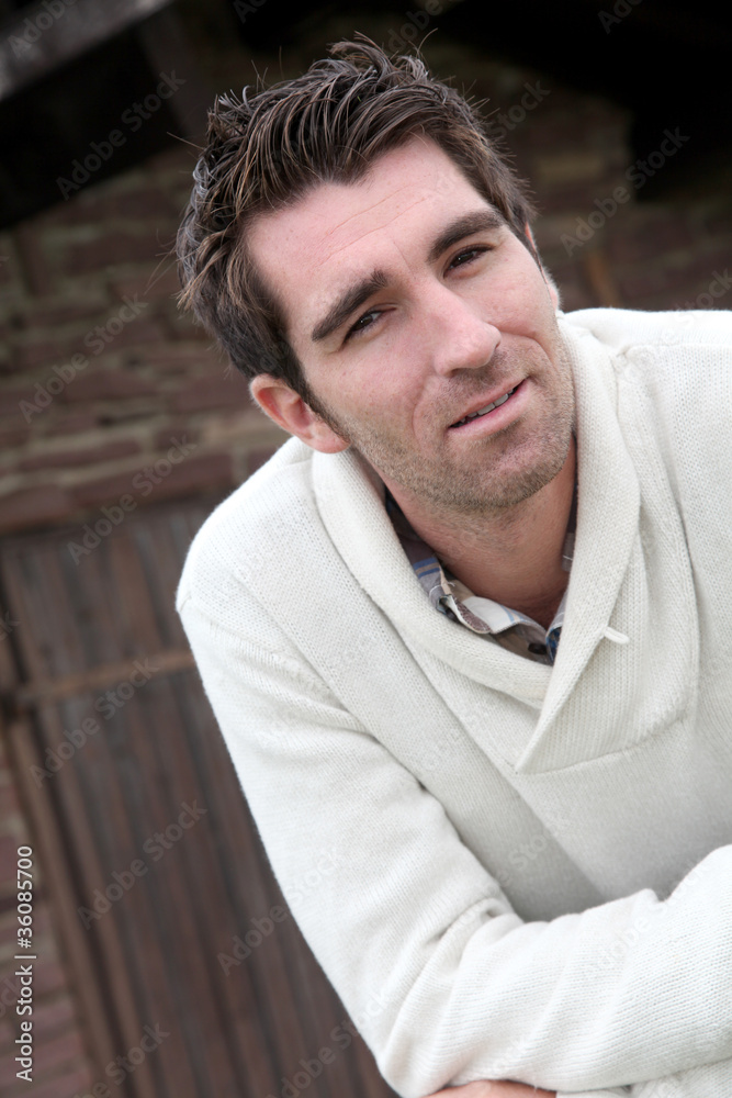 Fototapeta premium Smiling man standing in front of countryhouse