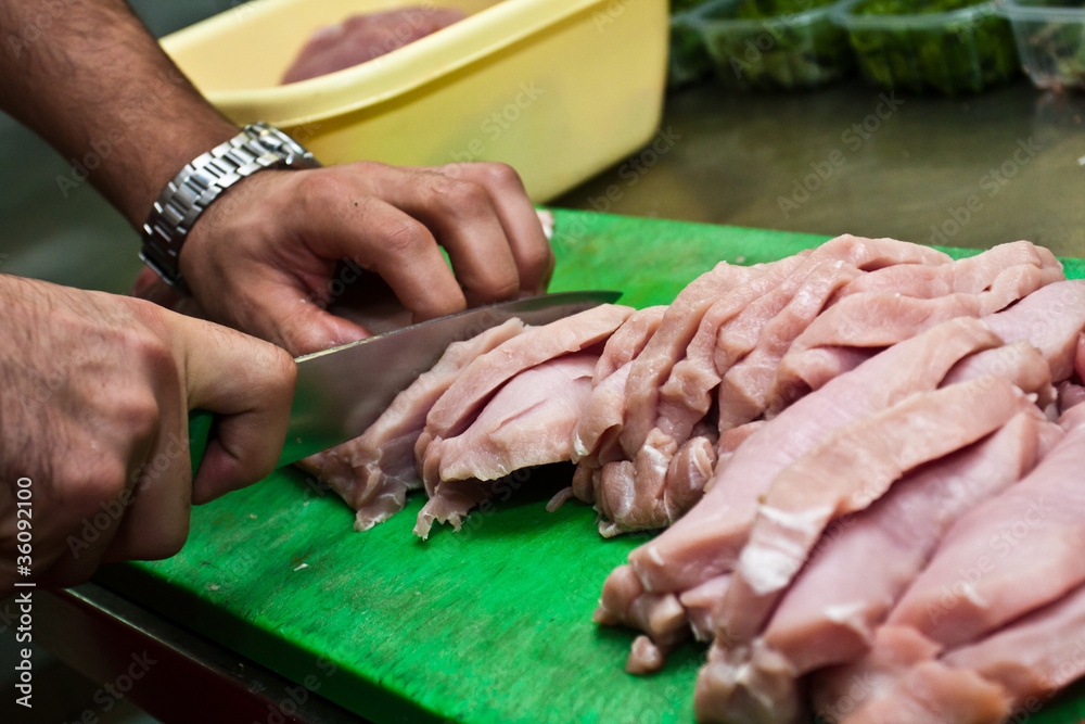 A cook cutting a meat